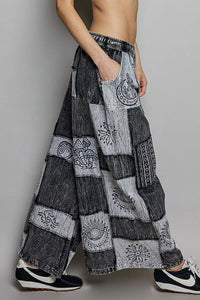 Person wearing a patchwork-style denim skirt with embroidered patterns on a plain background