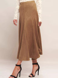 Brown suede skirt worn by a person on a plain background
