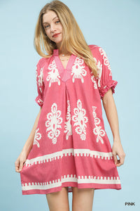 Woman wearing a pink dress with white patterns on a light blue background