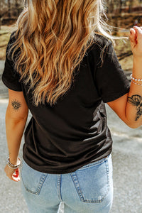 Person wearing a black t-shirt and light blue jeans with tattoos on arms.
