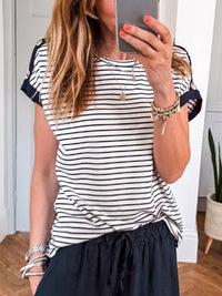 Person wearing a black and white striped shirt and navy pants, taking a mirror selfie.