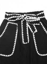 Black dress with white trim on a white background