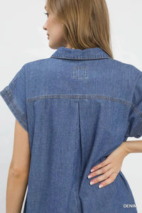 Woman wearing a blue denim dress with a plain background