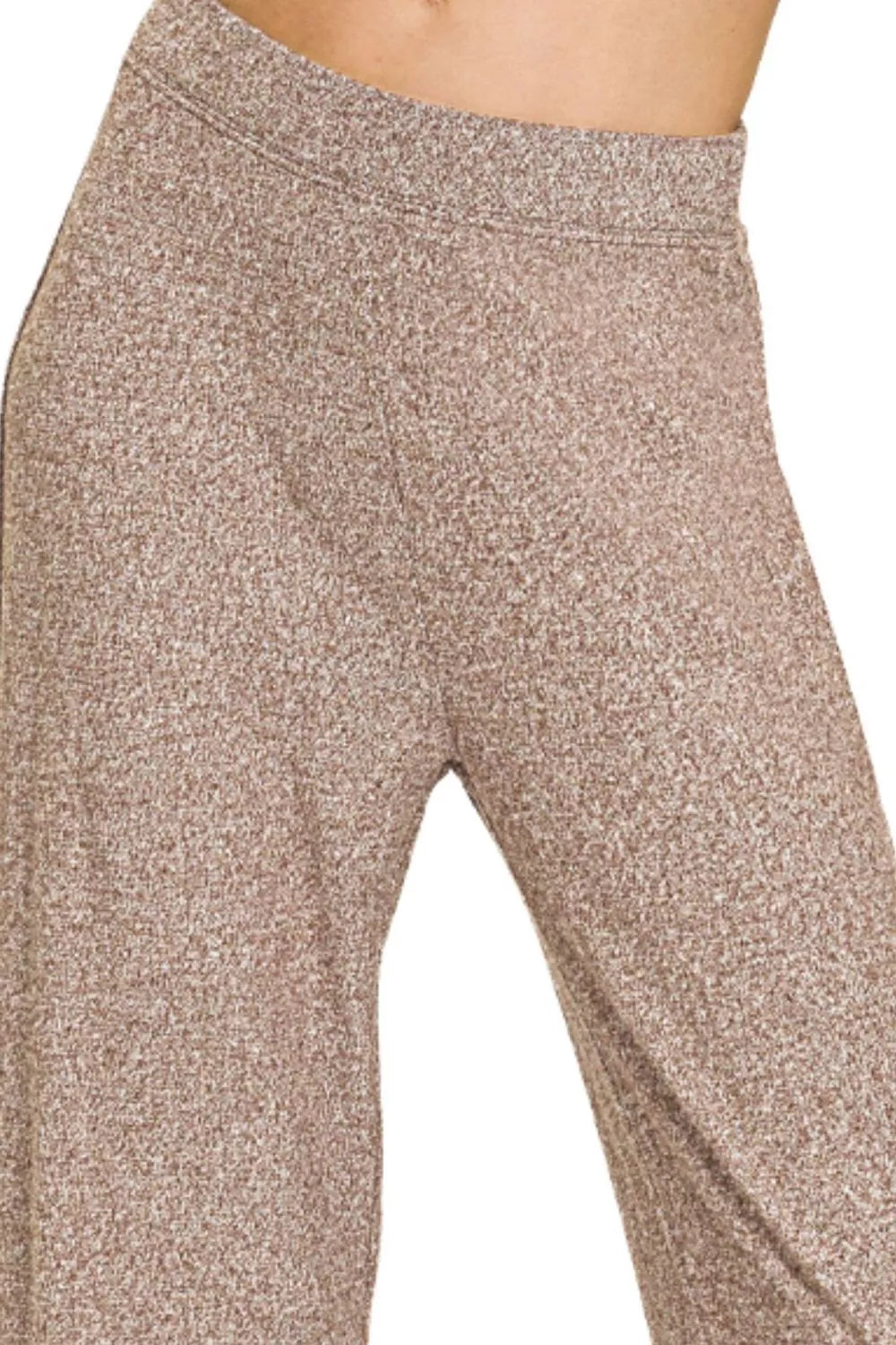 Close-up of beige leggings with a textured pattern on a plain background