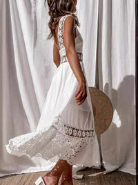Woman wearing a white dress with lace details standing in front of sheer curtains.