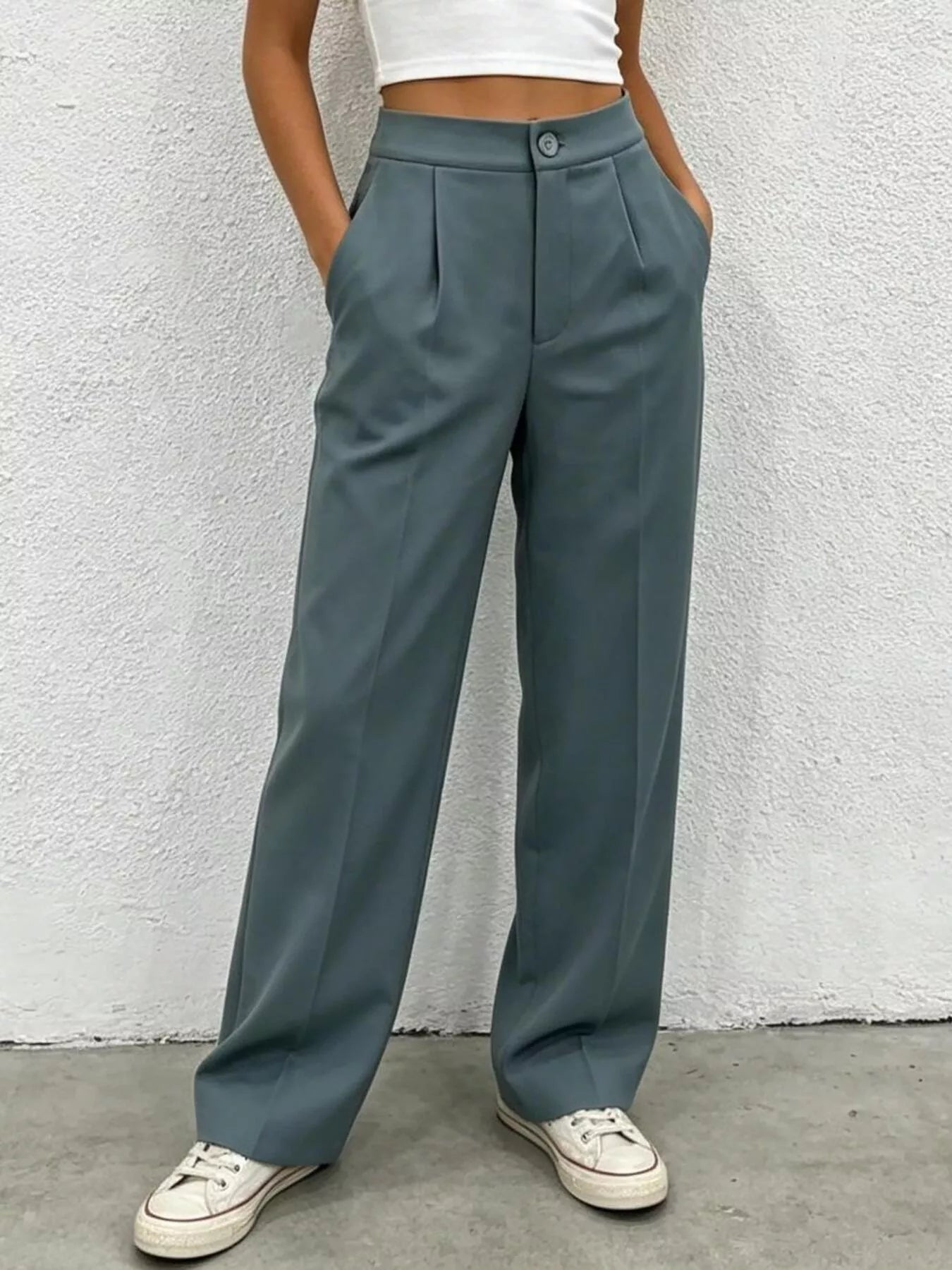 Person wearing teal wide-leg pants against a white wall