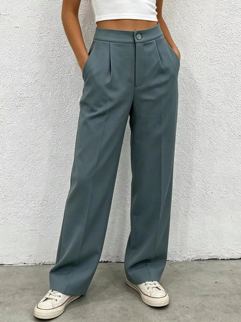 Person wearing teal wide-leg pants against a white wall