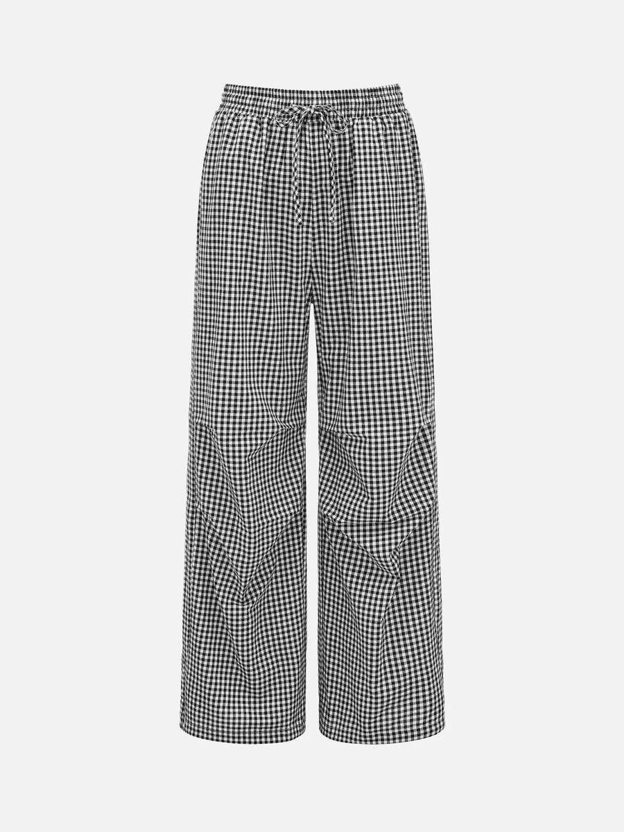 Black and white gingham wide-leg pants with an elastic drawstring waist and large patch pockets, shown on a light gray background.