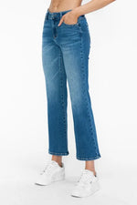Person wearing blue jeans and white sneakers on a white background