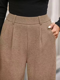 Close-up of brown pleated pants with a blurred background