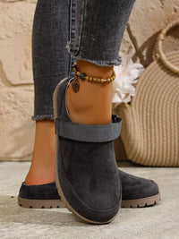 Dark gray ankle boots worn with rolled-up jeans on a neutral background