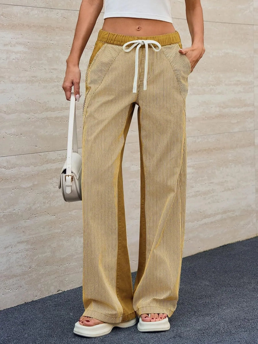 Person wearing beige and yellow striped pants with a white background