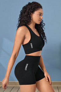 Woman wearing a black sports bra and shorts set with 'GymWear' branding against a blue background.