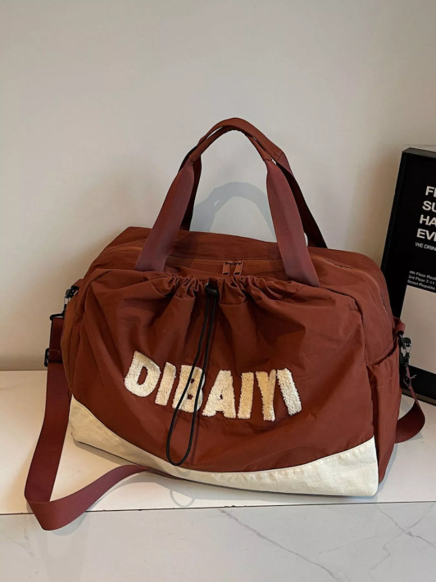 Brown duffel bag with 'Dubai' text on a white surface