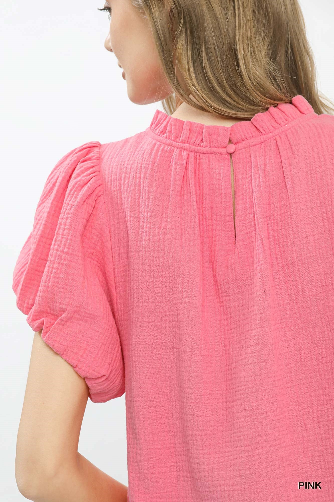 Close-up of a person wearing a pink top with puff sleeves on a white background