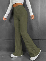 Person wearing green ribbed wide-leg pants and white sneakers against a gray background