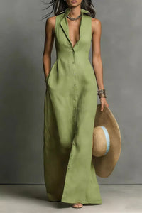 Woman wearing a long green dress holding a hat against a gray background