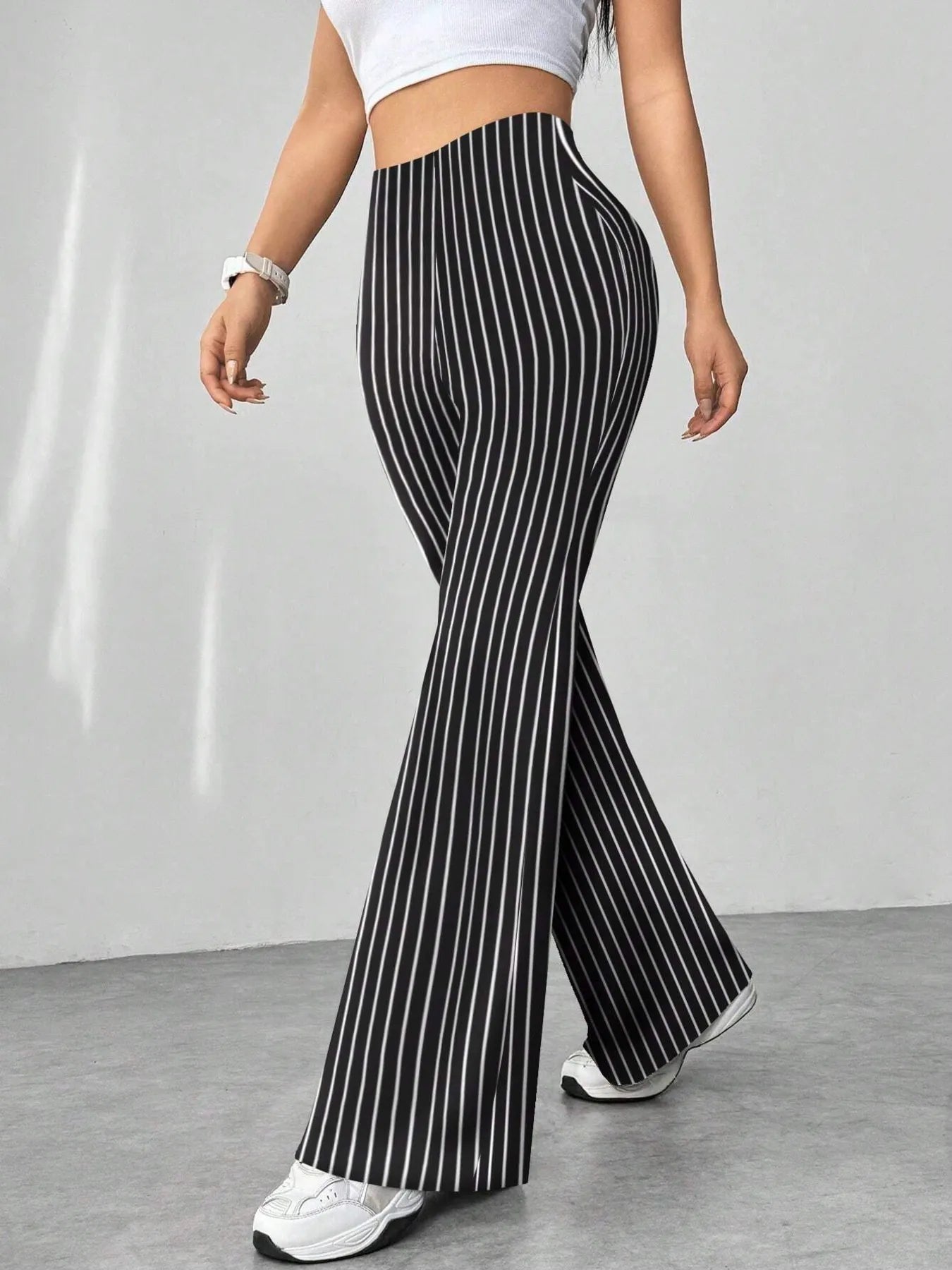 Person wearing black and white striped pants on a plain background