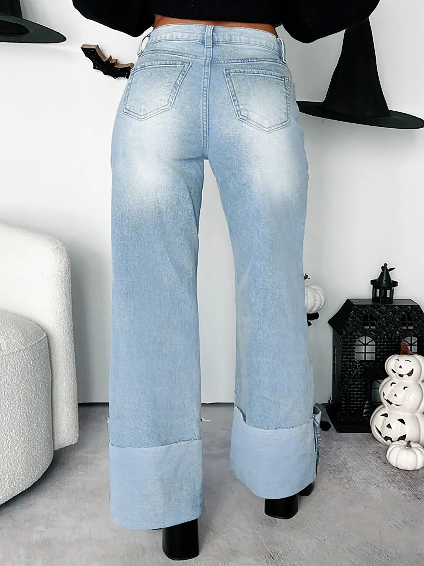 Light blue jeans worn by a person in a room with Halloween decorations.