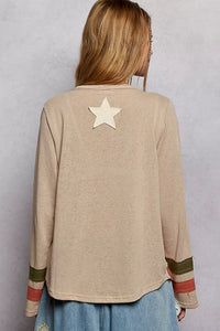 Person wearing a beige long-sleeve top with a star design on the back against a gray background
