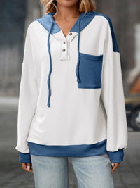 White and blue color-blocked sweater worn by a person with a blurred background