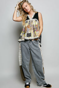 Woman wearing a patchwork top and jeans against a plain background