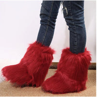 Red furry boots worn with blue jeans on a neutral background