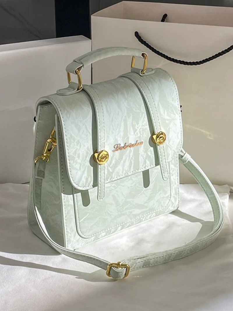 Light green handbag with gold accents on a white surface