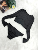 Black long-sleeve top and high-waisted shorts on a white surface with a magazine and flower in the background.