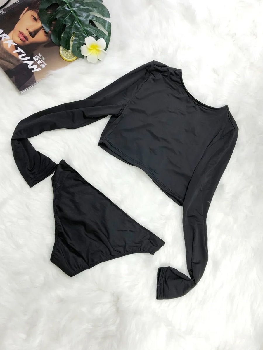 Black long-sleeve top and high-waisted shorts on a white surface with a magazine and flower in the background.