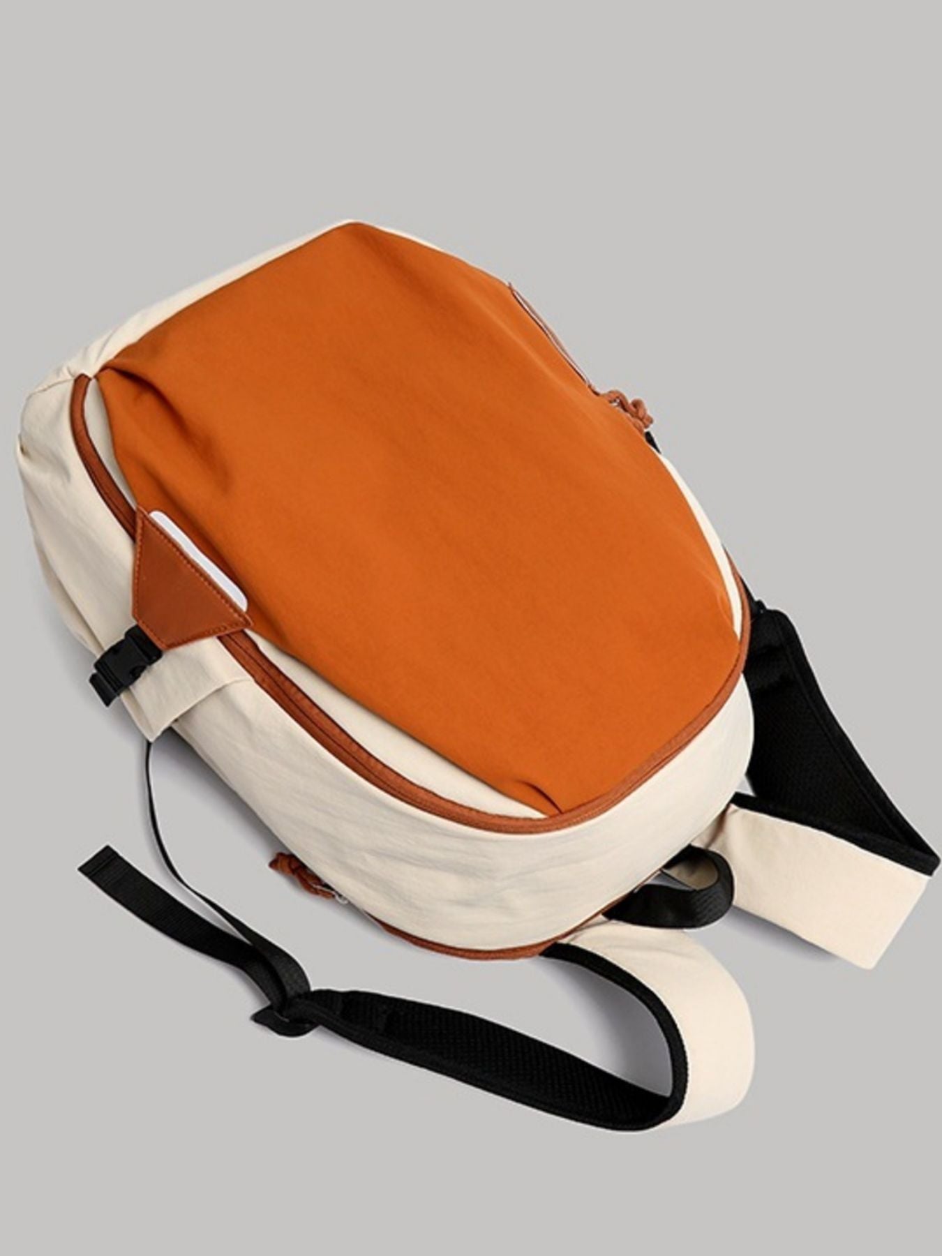 Two-toned backpack with orange top section and beige bottom section on a gray background
