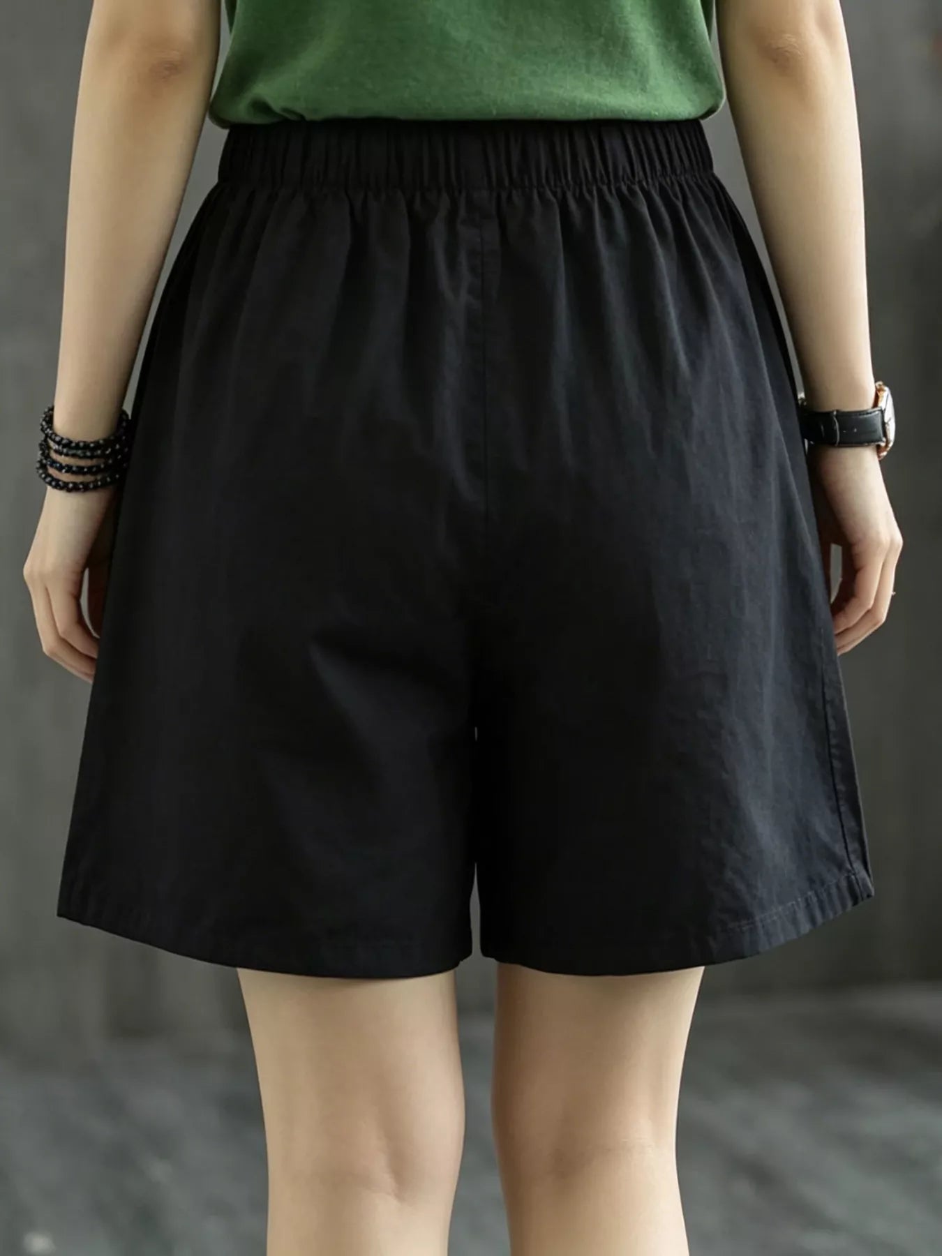 Person wearing black shorts and a green top against a neutral background
