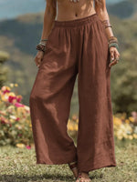 Person wearing brown wide-leg pants standing in a natural setting with flowers and mountains.