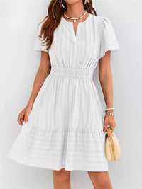 Woman wearing a white dress with a plain background
