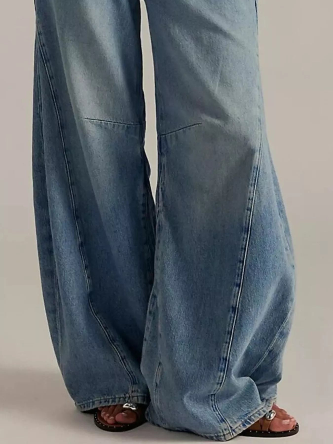 Blue jeans worn by a person on a plain background