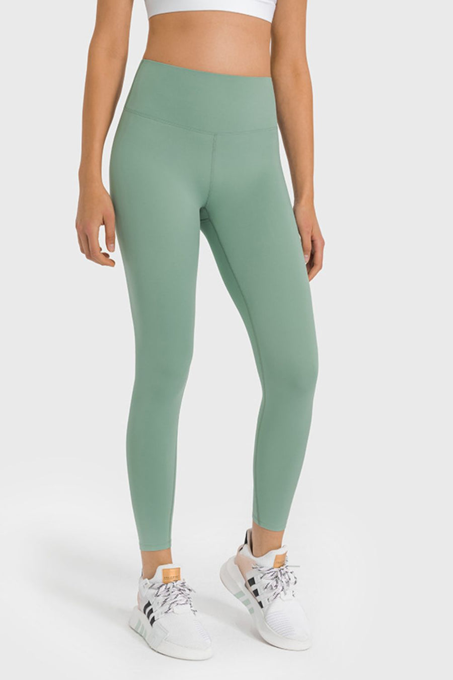 Person wearing green leggings and white sneakers on a white background