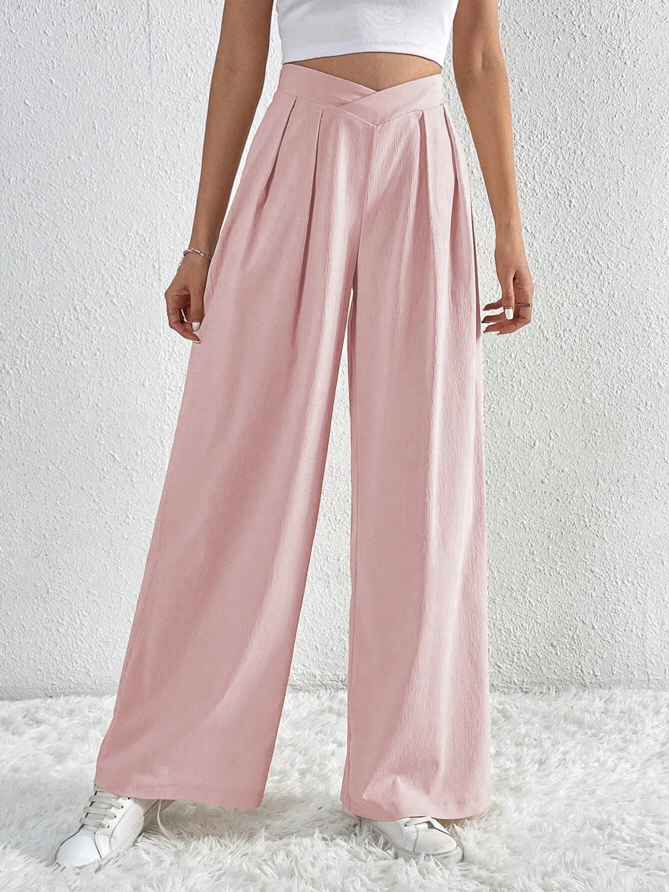 Person wearing light pink wide-leg pants on a white background