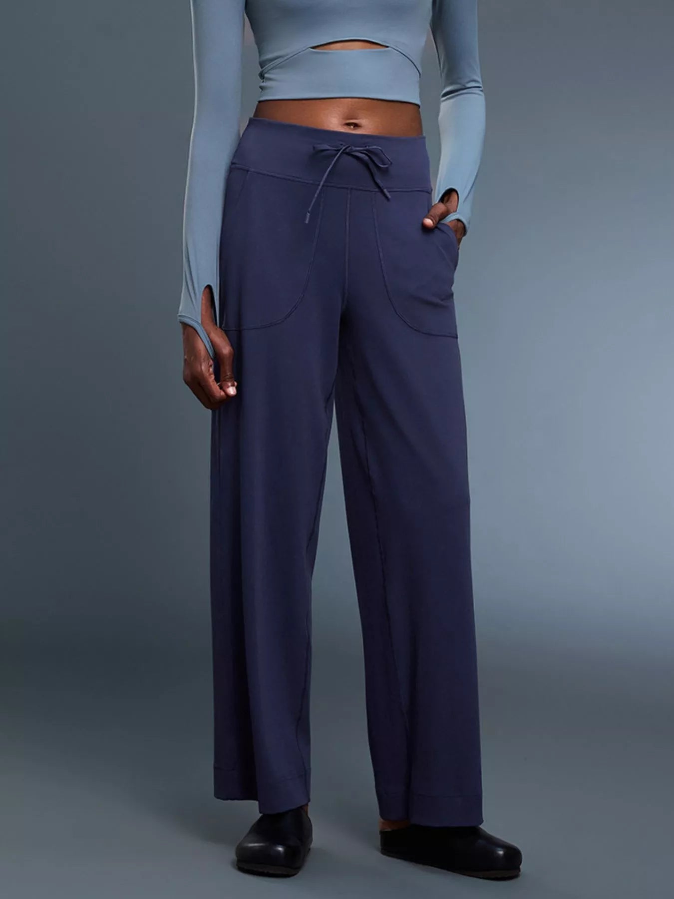 Person wearing a light blue crop top and dark blue pants on a gray background