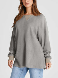 Woman wearing a gray oversized sweater and blue jeans on a light gray background