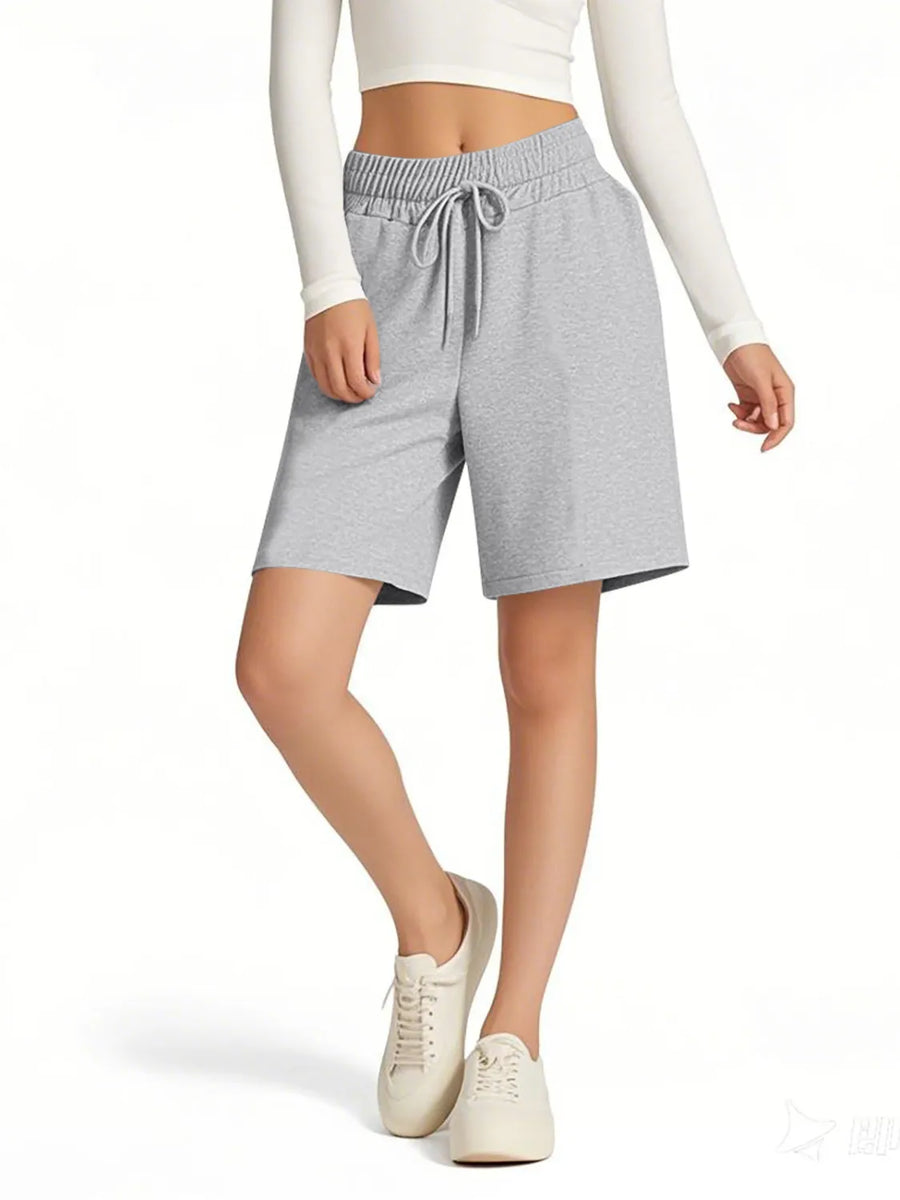 Person wearing gray shorts with a white top on a white background