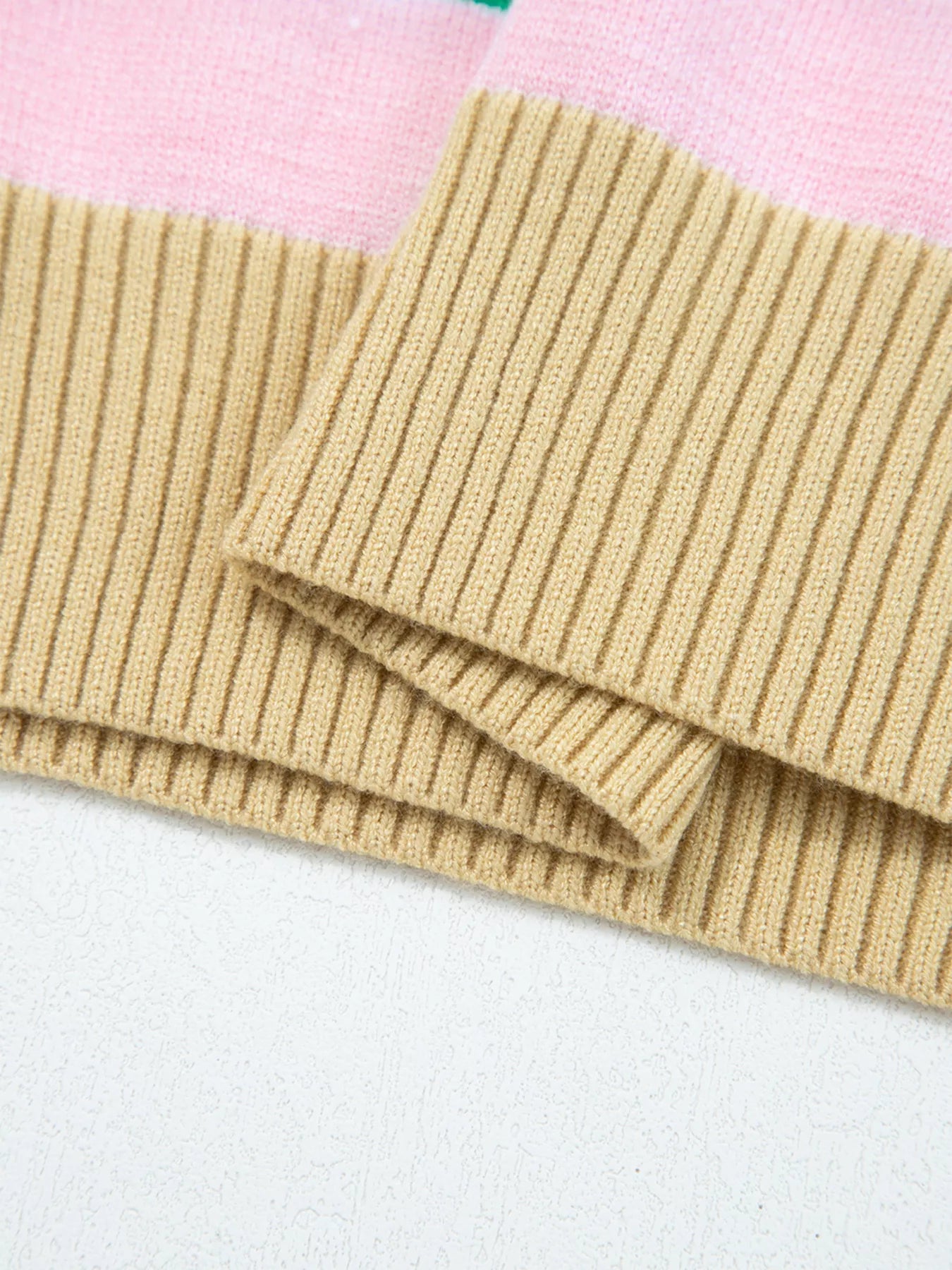 Folded beige knitted fabric on a light pink background