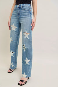 Blue jeans with star patterns worn by a person on a plain background