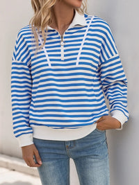 Person wearing a blue and white striped long-sleeve shirt with a plain background