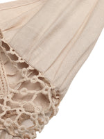 Close-up of beige lace fabric with intricate patterns on a white background