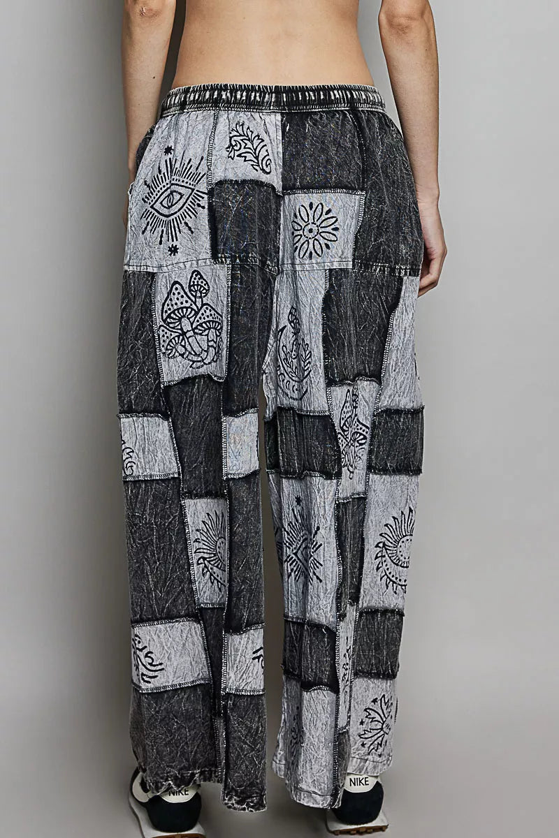 Person wearing a pair of black and white patterned pants on a plain background