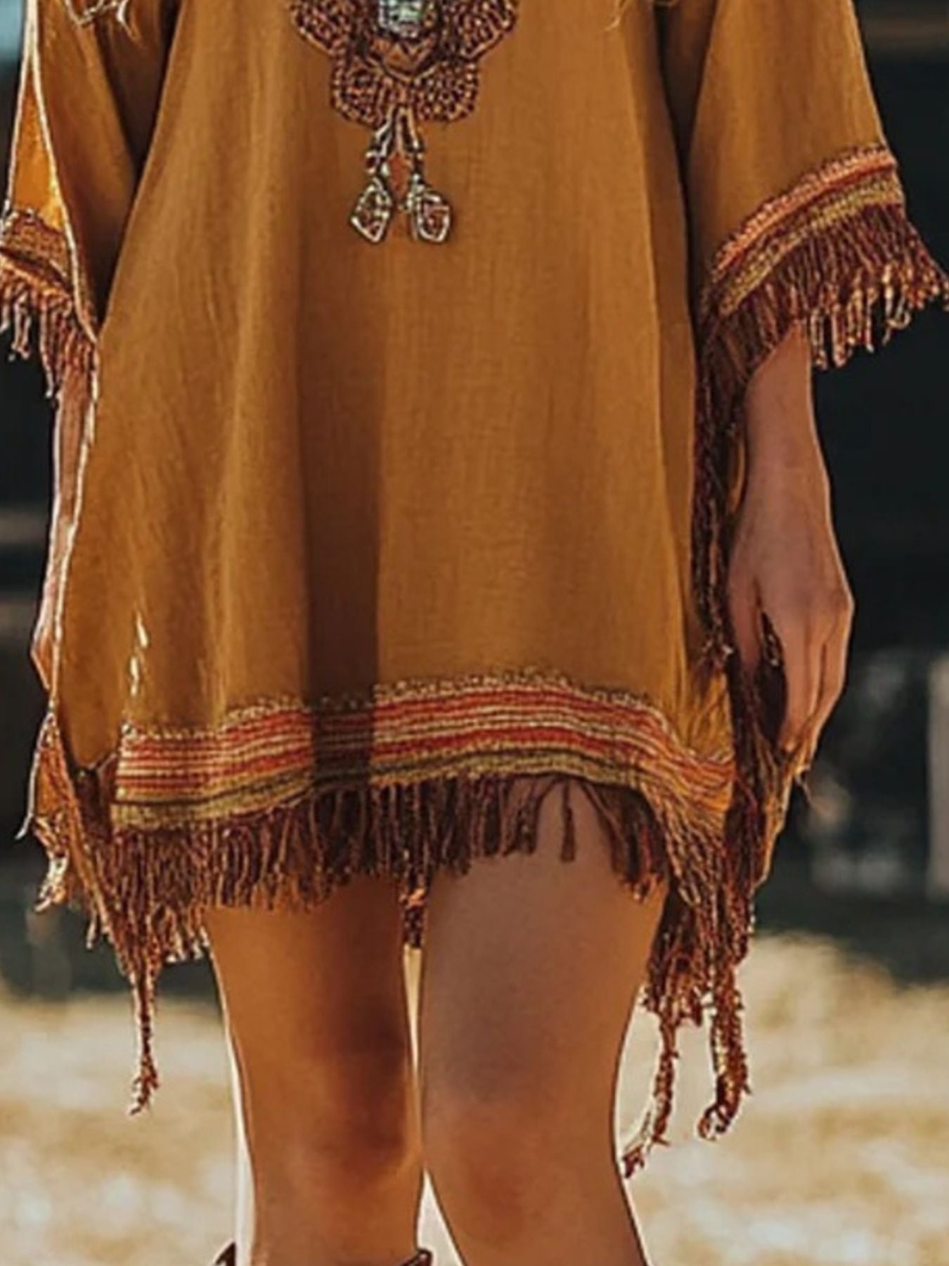 Mustard yellow dress with fringe details on a blurred background