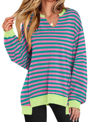 Woman wearing a colorful striped sweater with green, pink, and blue horizontal stripes on a white background.