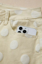Phone in a pocket of beige pants with white polka dots