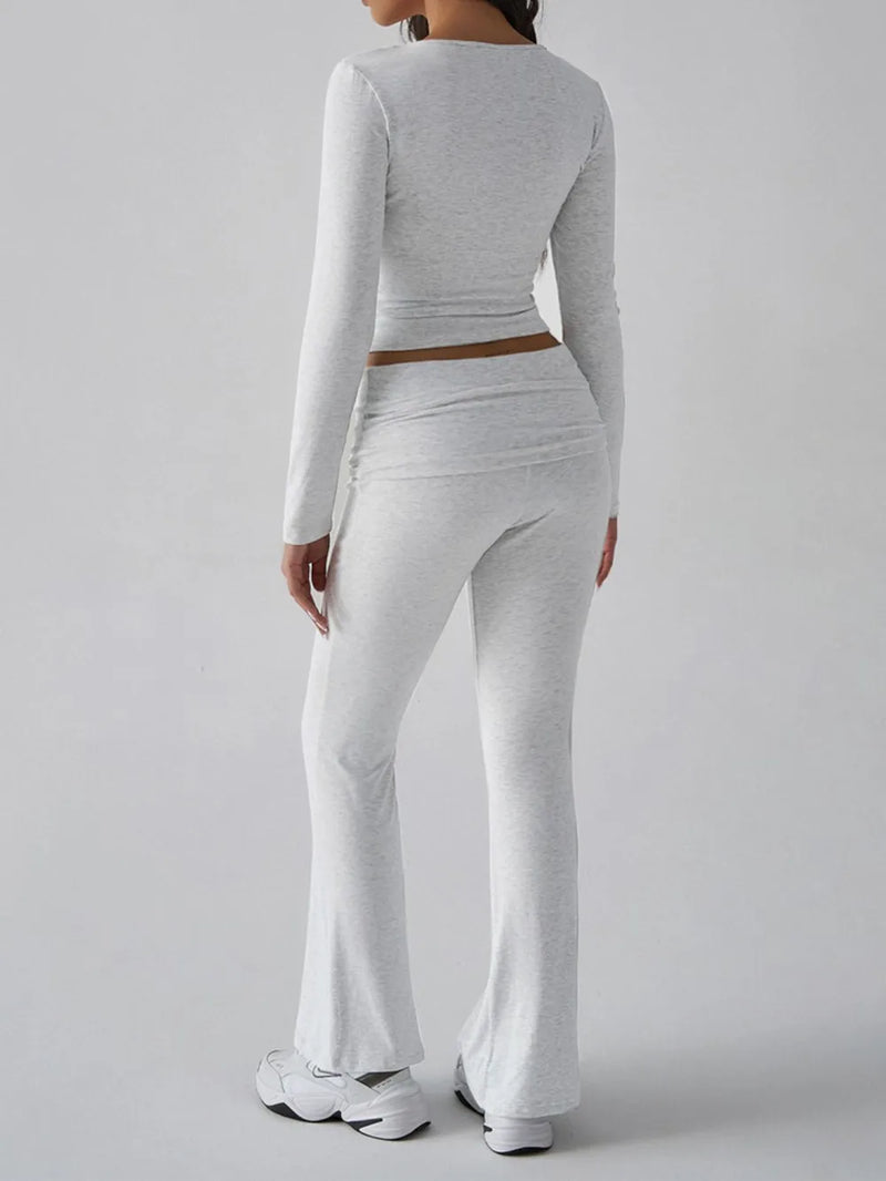 Person wearing a gray long-sleeve top and flared pants on a plain background