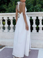 Woman wearing a white dress with a backless design, standing outdoors.